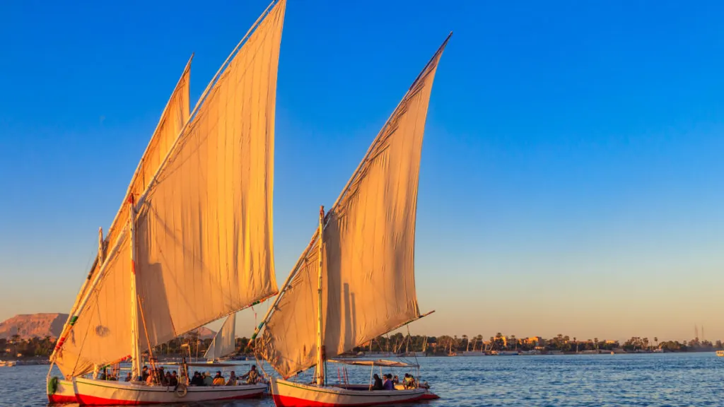 Two traditional felucca sailing boats on the River Nile in warm evening light