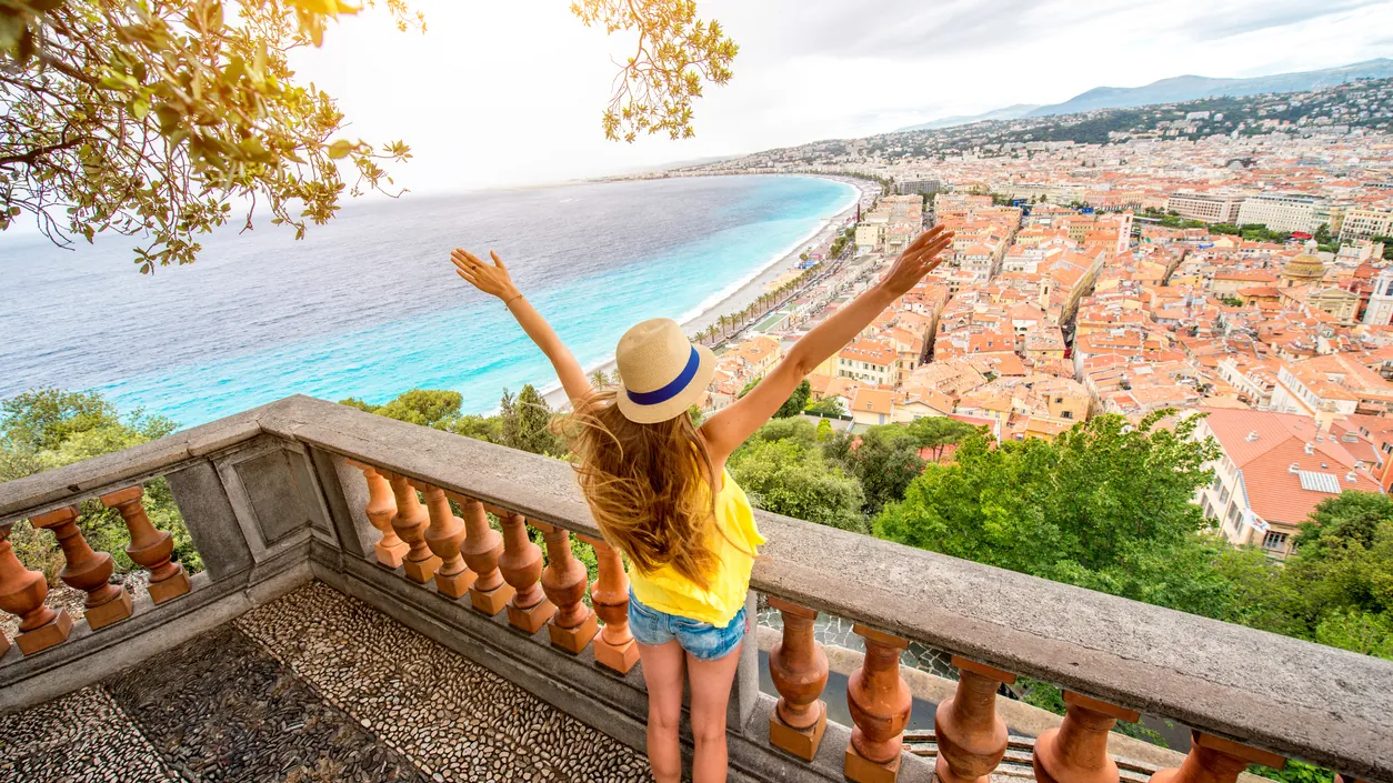 A visitor on a balustraded terrace overlooking Nice and the curve of the Baie des Anges