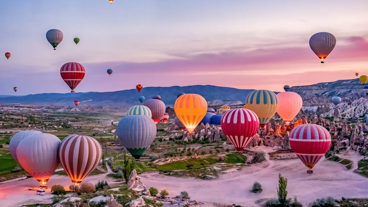 Colourful hot-air balloons preparing to launch over the valleys of Göreme National Park in Cappadocia