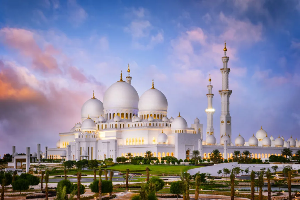The white domes and minarets of the Sheikh Zayed Grand Mosque in Abu Dhabi at dusk