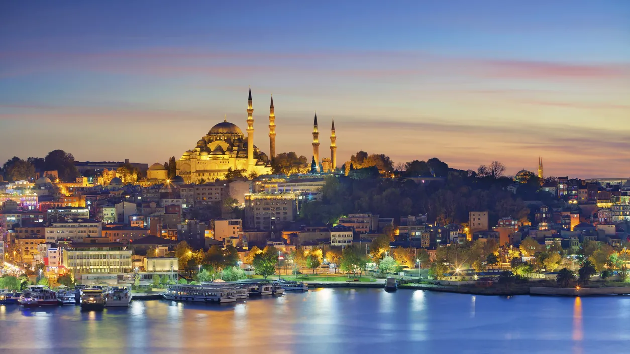 Istanbul’s Süleymaniye Mosque lit up above the city and the water at dusk
