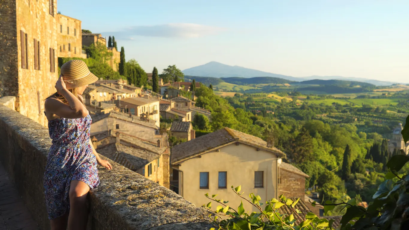 A visitor looking out from a stone village terrace over the rolling hills of the Tuscan countryside